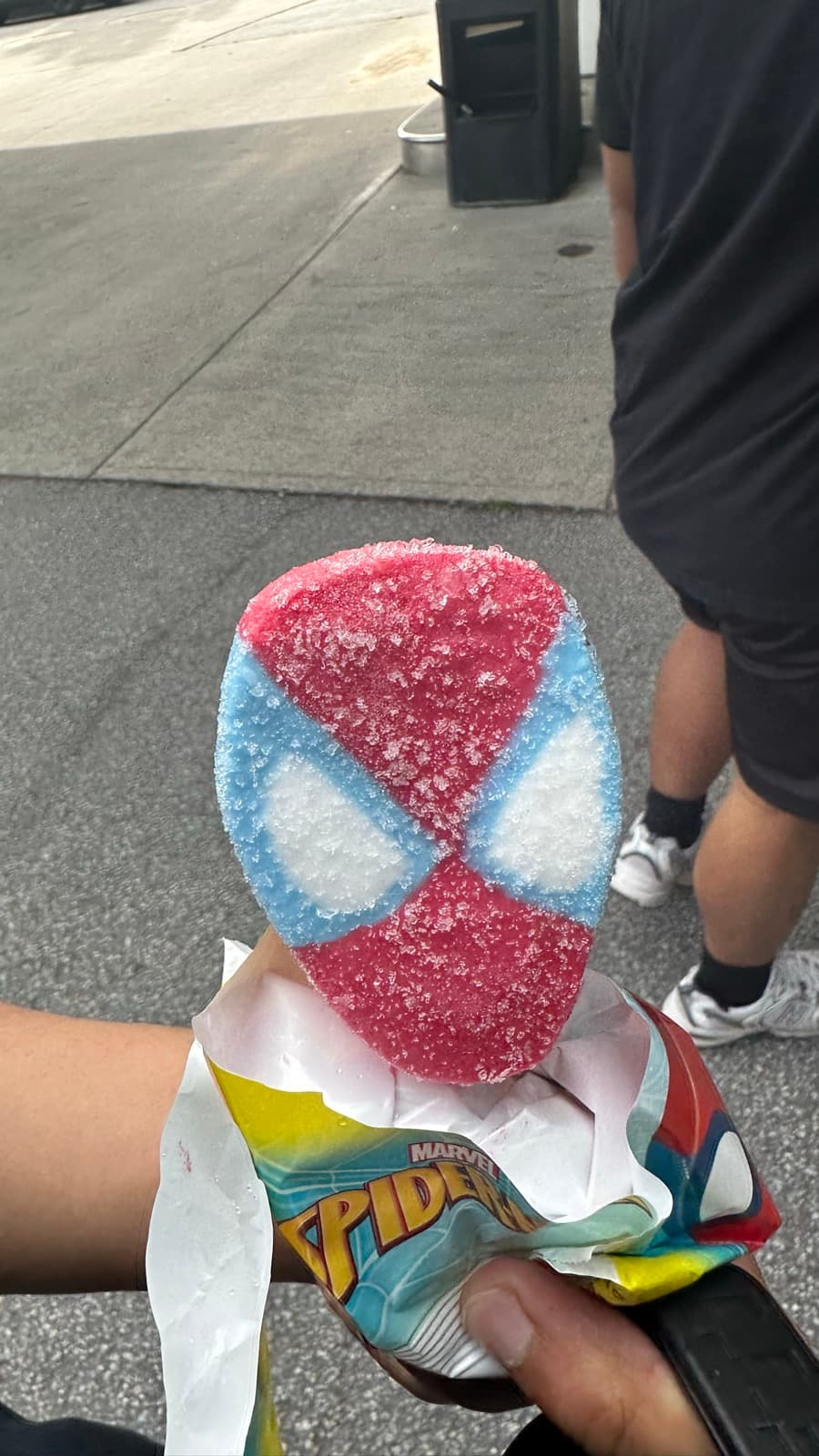 A Spider-Man face popsicle in its wrapper.